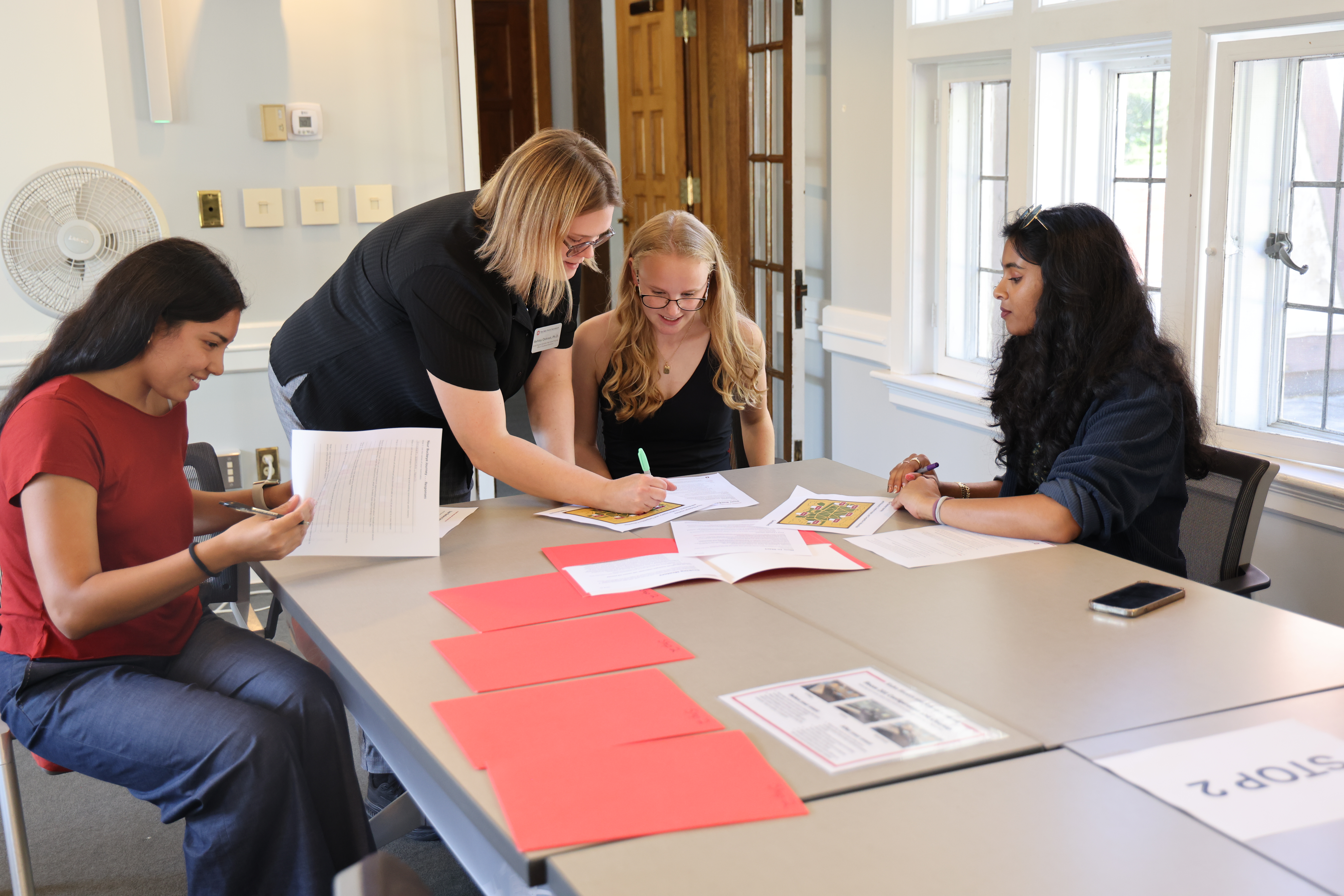 Four people are gathered around a table sitting and engaging with the materials.
