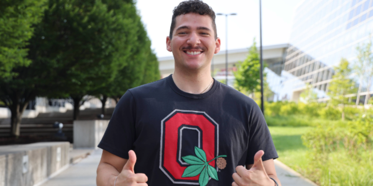 Cordell Rubio holds two thumbs up with black shirt with red block "O" and buckeye nut and leaf combo 