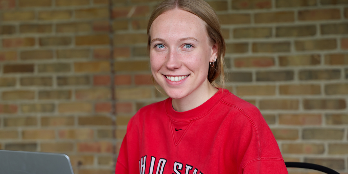 A person with light hair, wearing a red Ohio State shirt, is smiling at the camera.