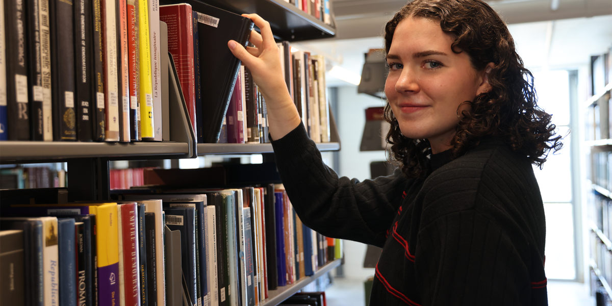 Ohio State student smiling as she grabs a book in the library