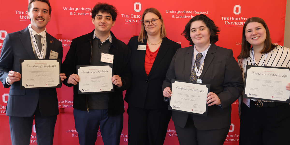 Denman awardees showcase certificates in front of red Ohio State backdrop