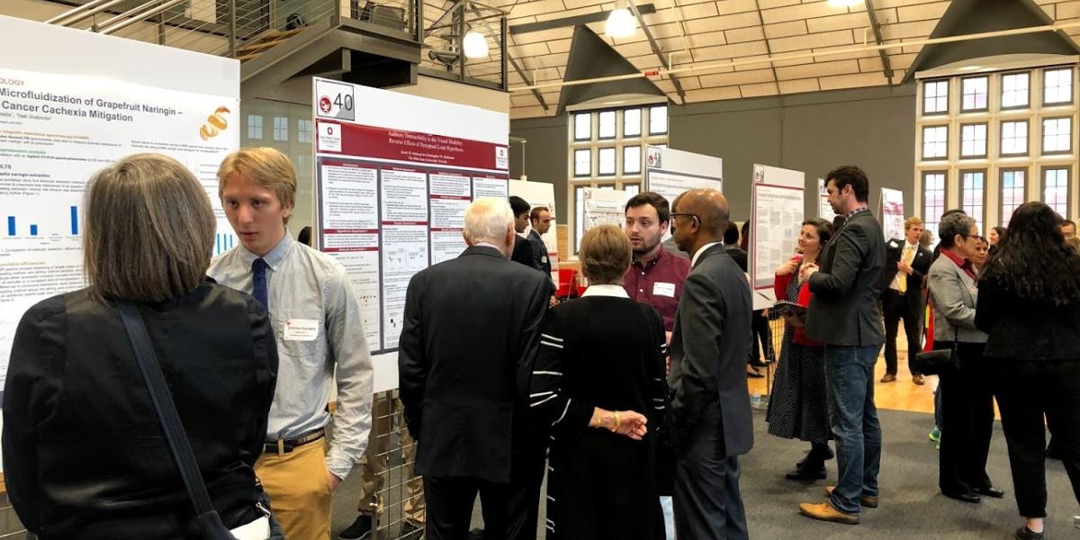 Students speak to forum attendees in front of their project posters