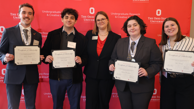 Denman awardees showcase certificates in front of red Ohio State backdrop
