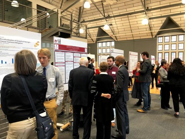 Students speak to forum attendees in front of their project posters