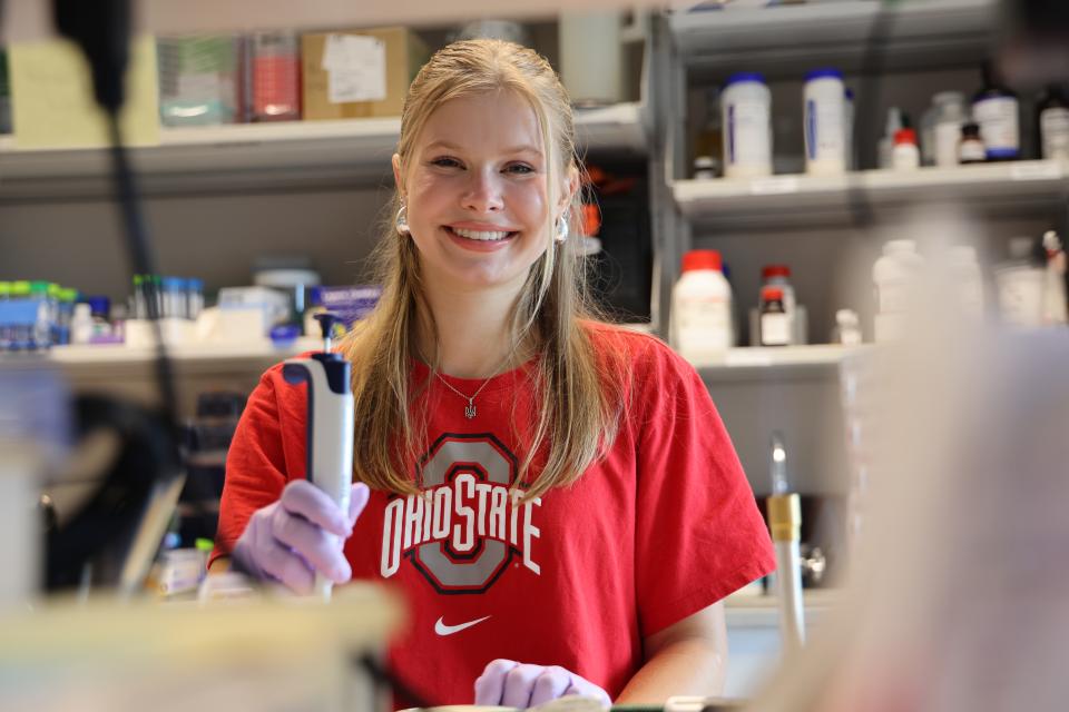 Kalyna smiles holding research tool in Ohio State shirt