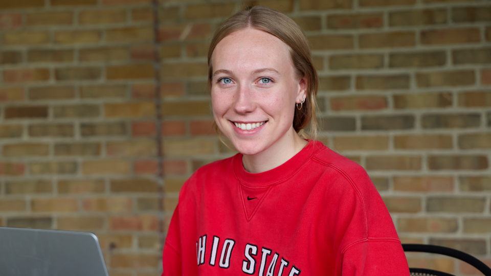 A person with light hair, wearing a red Ohio State shirt, is smiling at the camera.