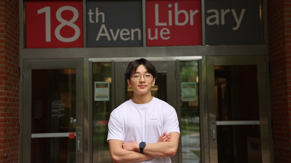 Justin Lee stands with arms crossed in front of 18th Avenue Library