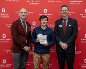 Dr. Alex Michaud accepts mentor award with two others in front of a red ohio state logo'd wall