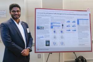 Adithya Ramaswami standing in front of his research poster